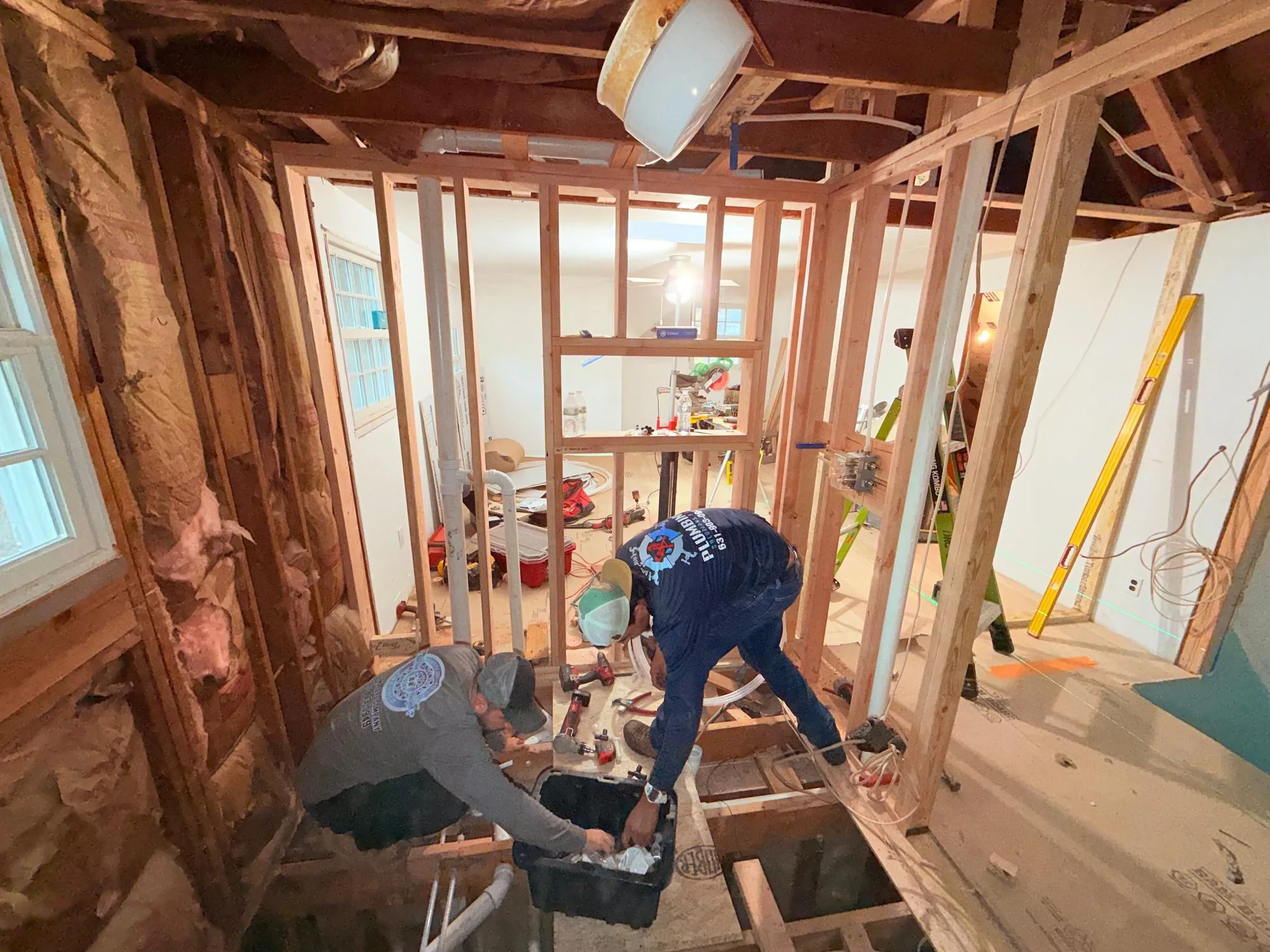 Plumbing Solutions P.A. technicians running new drain lines through an opened floor during a home renovation