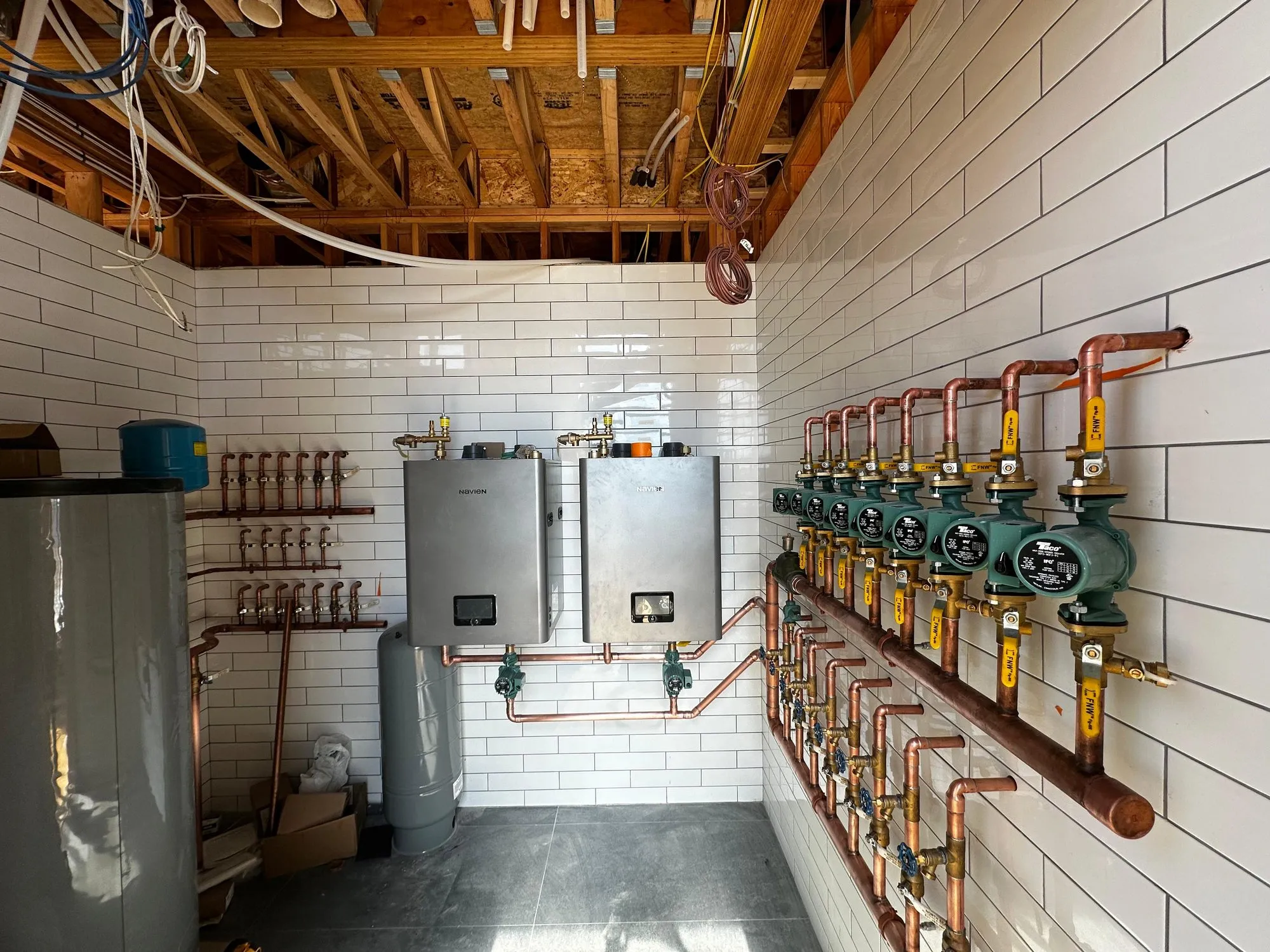 Hydronic heating system with paired tankless units and a bank of circulator pumps on copper headers