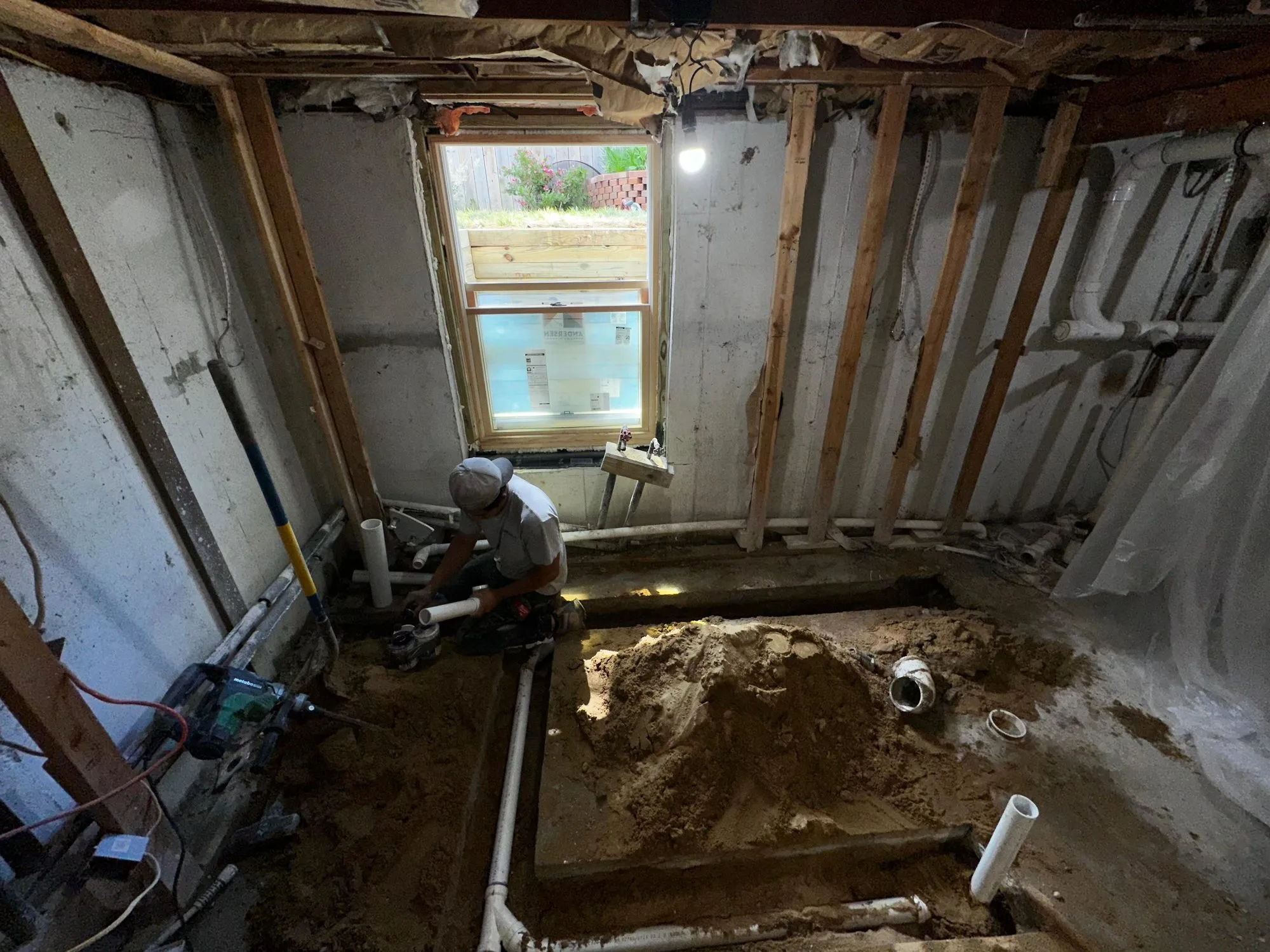 Technician cutting in a new drain line in an opened basement floor