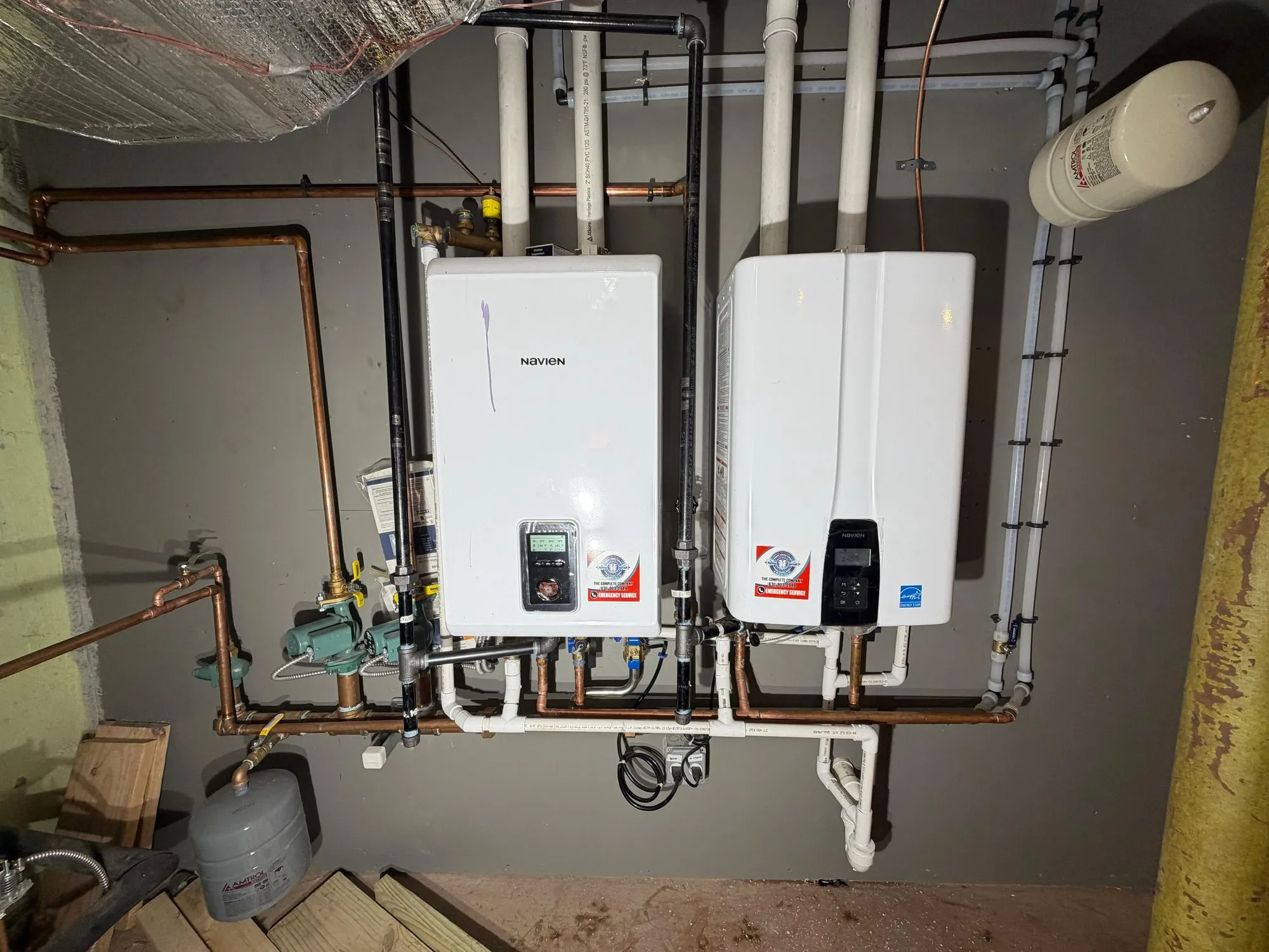 Two wall-hung Navien tankless water heaters installed on a copper manifold