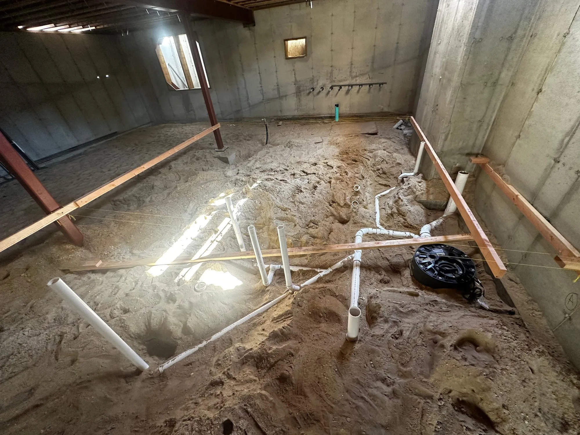 Under-slab drain, waste and vent piping laid out in sand before a concrete pour