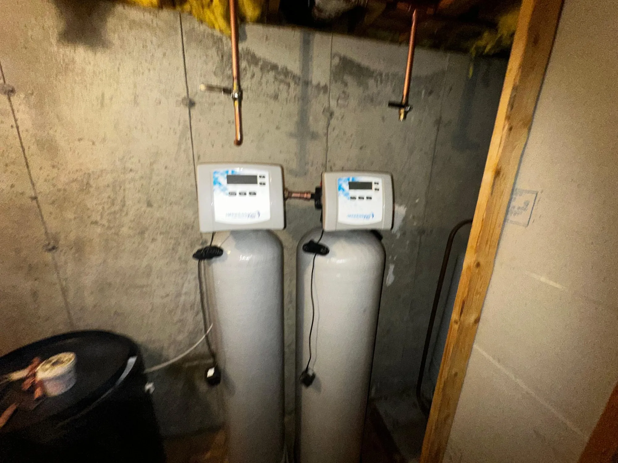 Twin-tank water softener system with control heads installed in a basement
