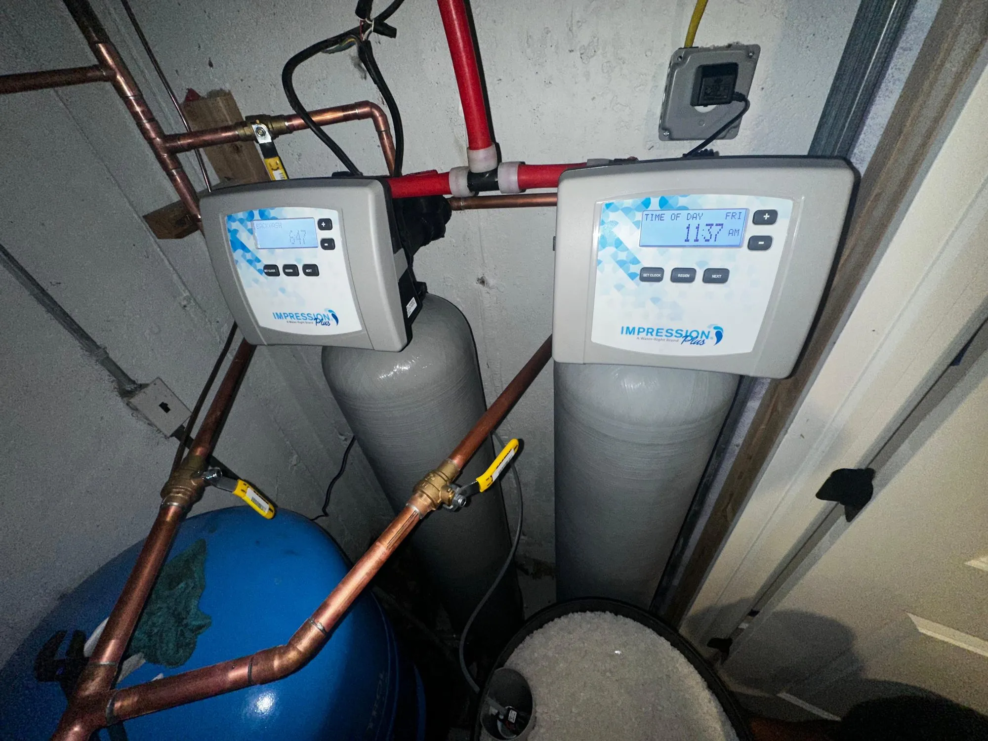 Twin water filtration tanks installed next to a well pressure tank
