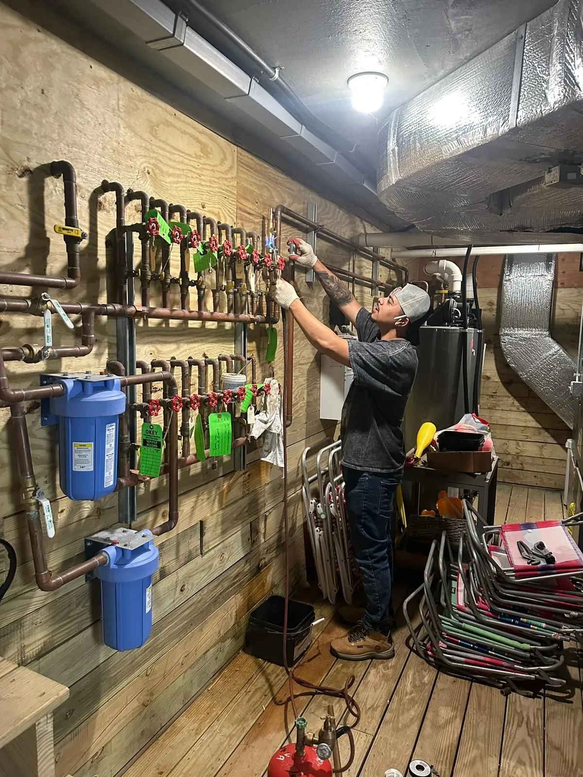 Plumbing Solutions P.A. technician working at a copper manifold wall with cartridge water filters