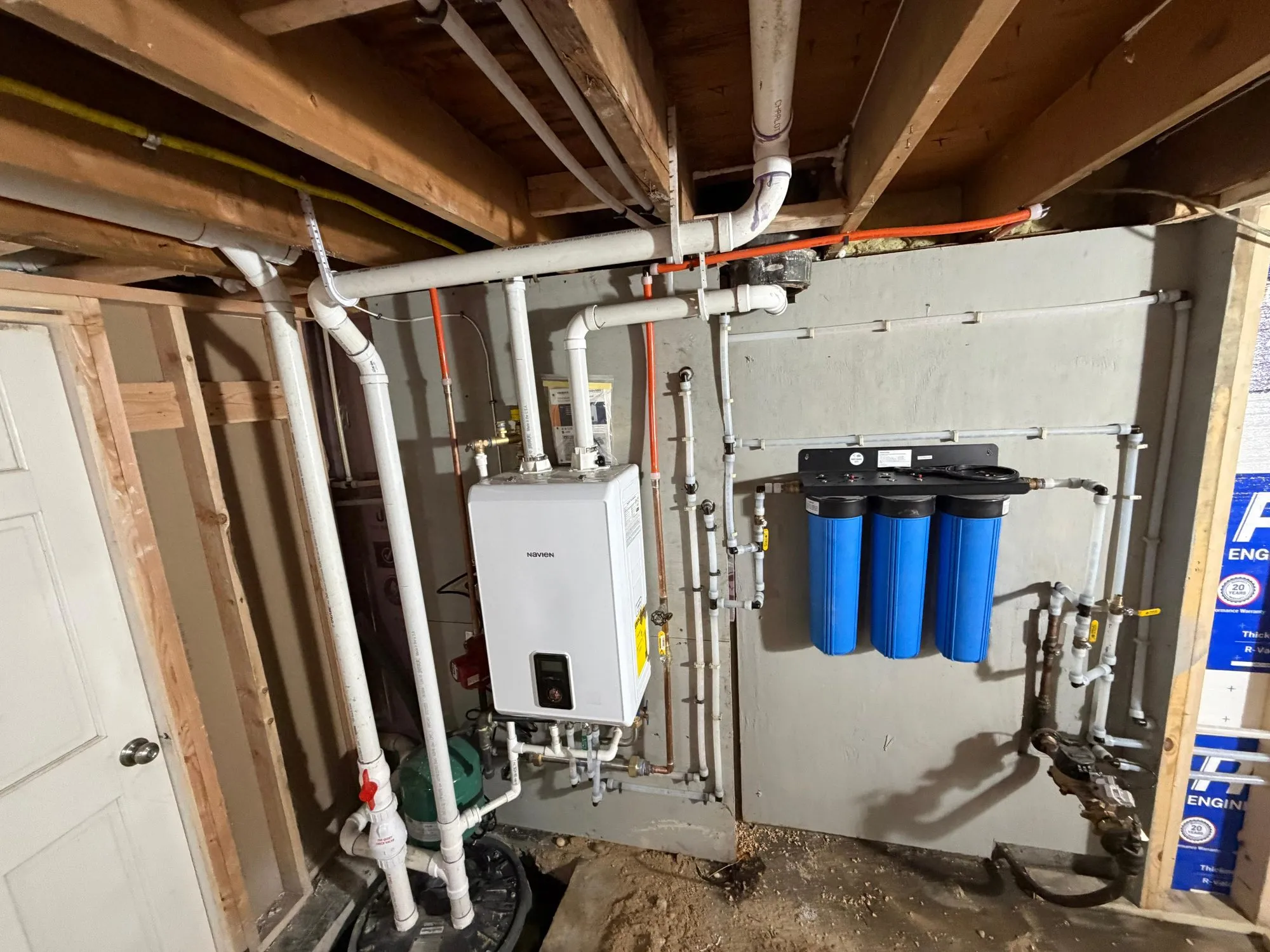 Tankless water heater installed beside three whole-house water filter housings